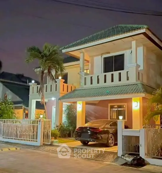 Charming two-story house with carport and lush palm tree at night
