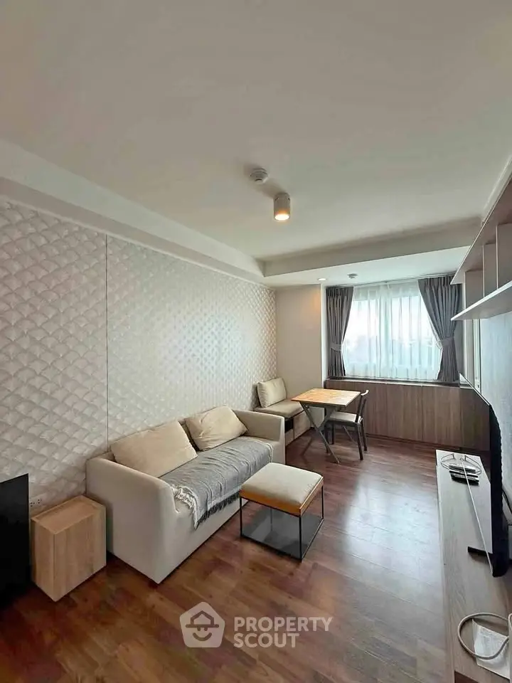 Modern living room with stylish decor and natural light, featuring cozy seating and a sleek entertainment unit.