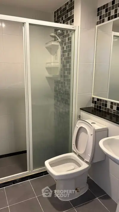 Modern bathroom with shower and toilet in sleek tiled design.