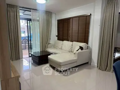 Modern living room with white leather sofa and large windows for natural light.