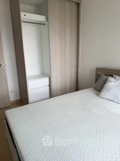 Modern bedroom with minimalist design featuring a comfortable bed and built-in wardrobe.
