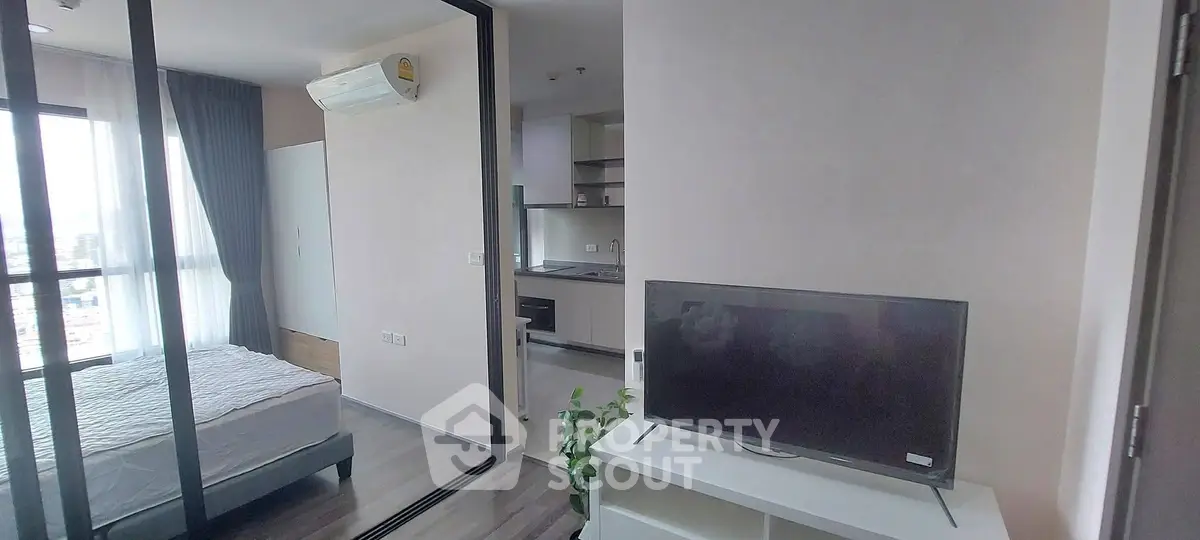 Modern apartment interior with bedroom and living area, featuring sleek design and natural light.
