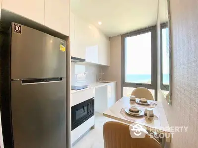 Modern kitchen with ocean view, sleek appliances, and cozy dining area