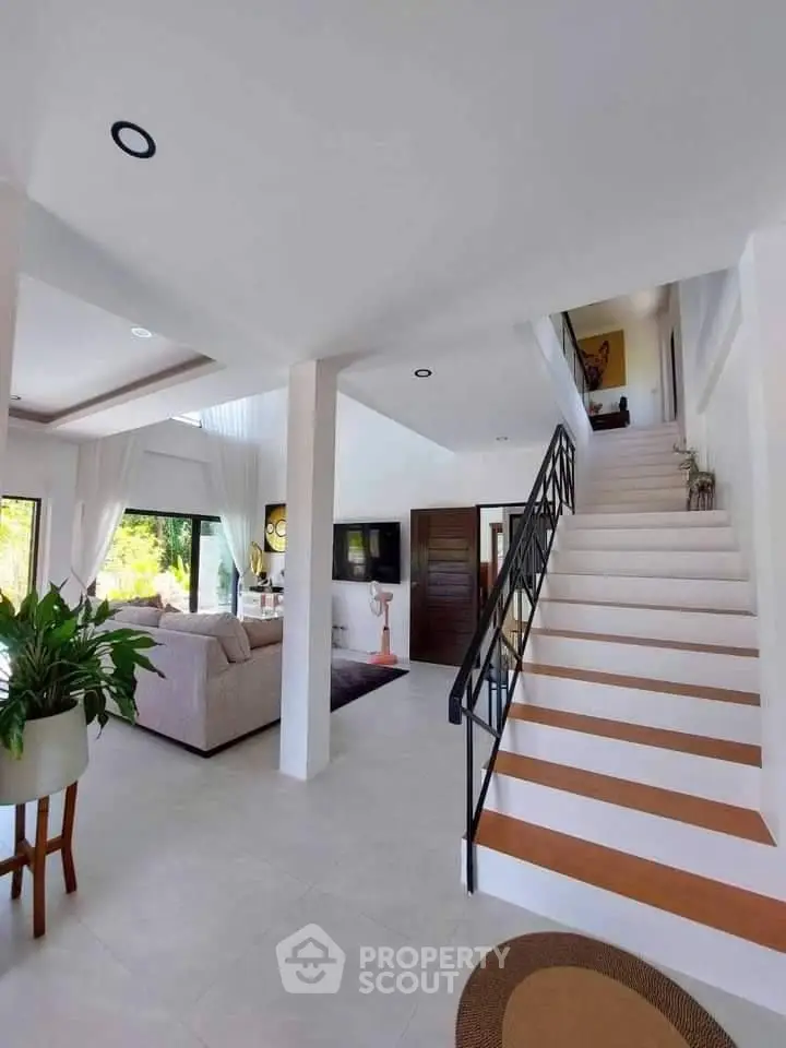 Elegant open-plan living space with high ceilings, modern staircase, and tasteful decor, perfect for sophisticated urban living.