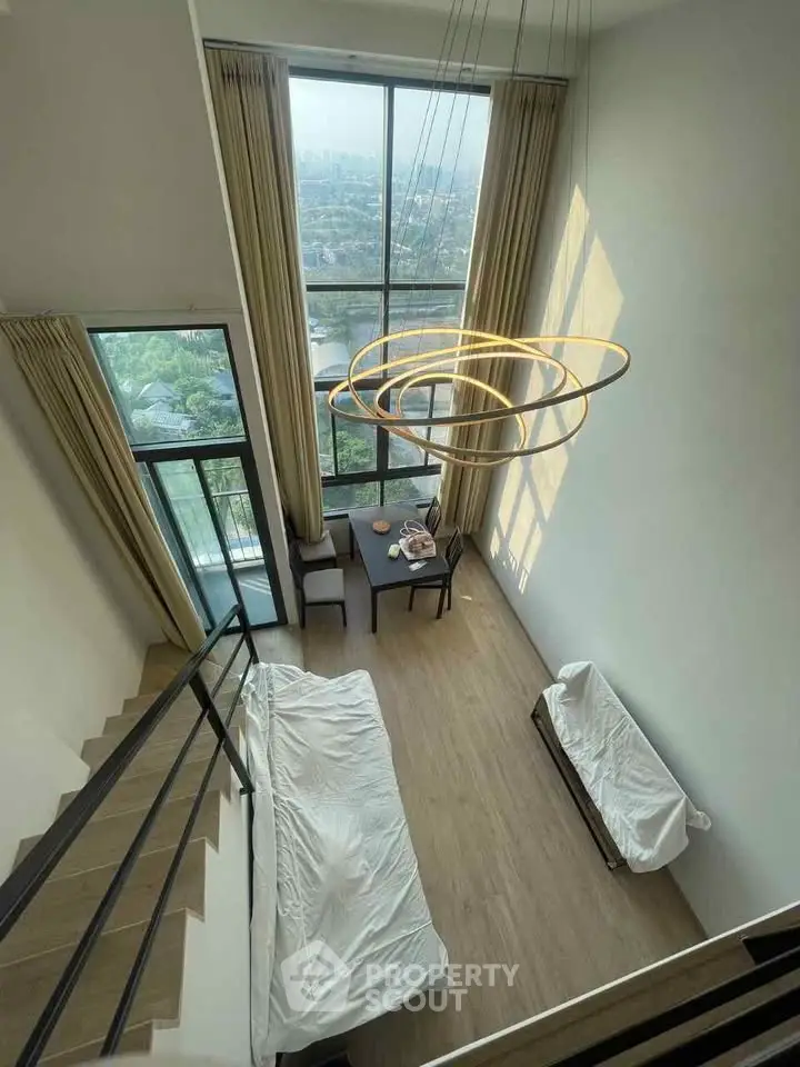 Stunning high-ceiling living room with floor-to-ceiling windows and modern chandelier.
