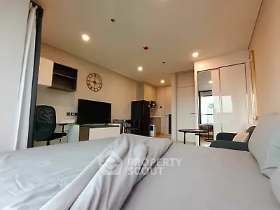Modern studio apartment with sleek design and cozy furnishings, featuring a compact kitchen and workspace.