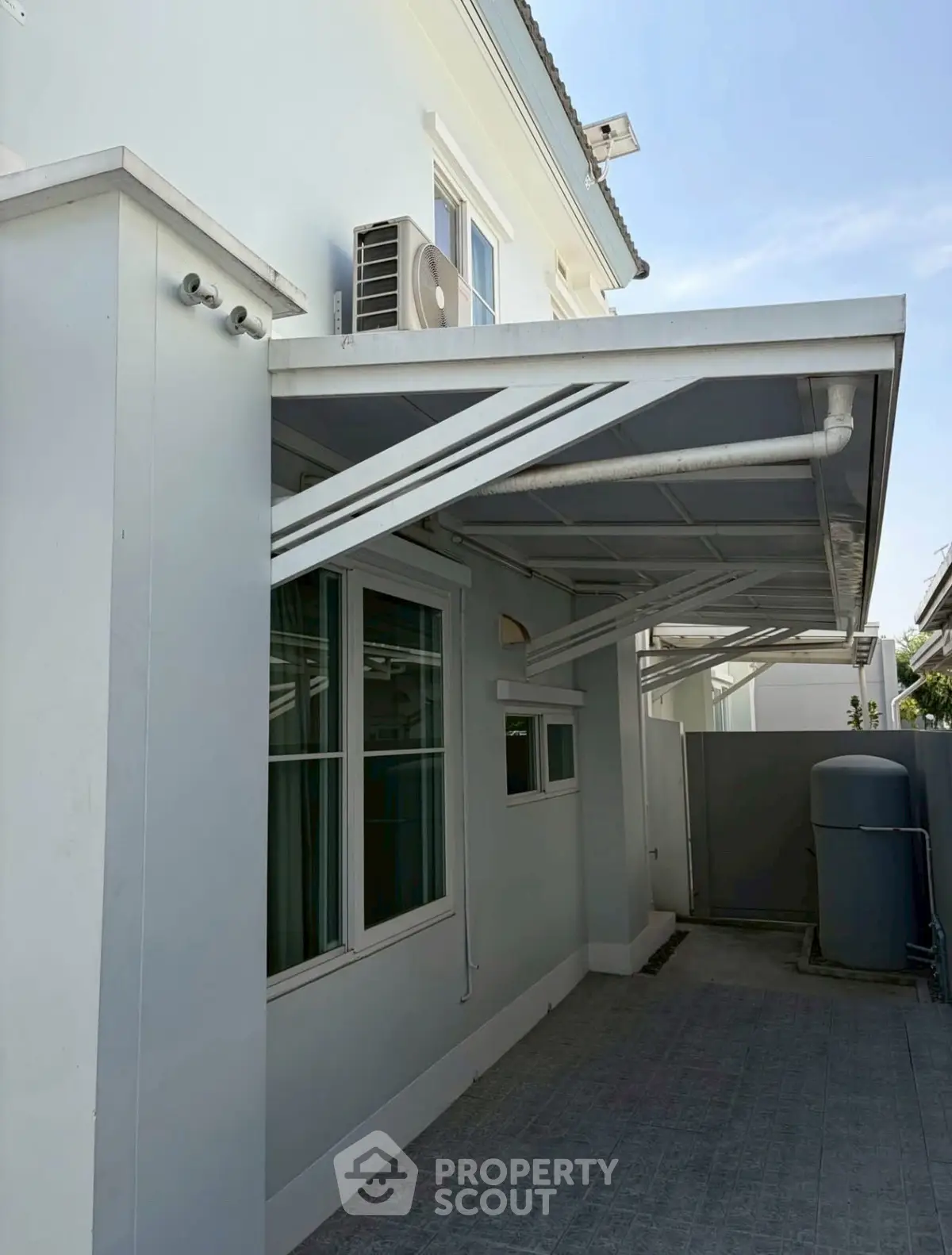 Modern exterior view of a residential building with air conditioning unit and covered walkway.