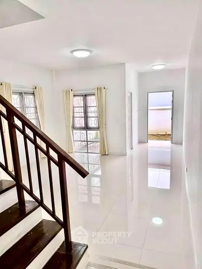 Spacious and bright interior with modern staircase and large windows, perfect for family living.