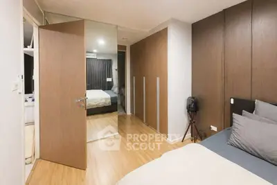 Modern bedroom with wooden flooring and mirrored closet doors in a stylish apartment.