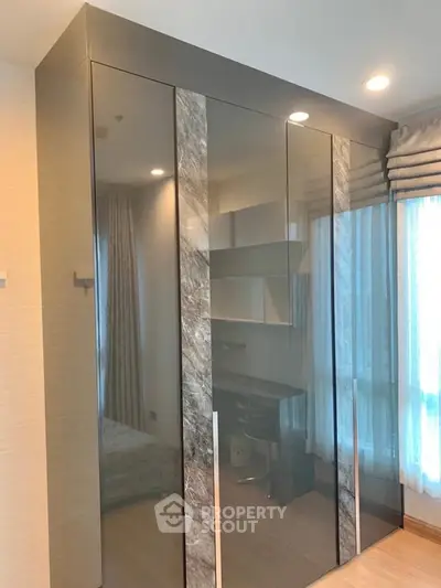 Modern bedroom with sleek mirrored wardrobe and natural light