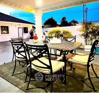 Charming outdoor patio with elegant dining set and lush greenery, perfect for entertaining and relaxation.
