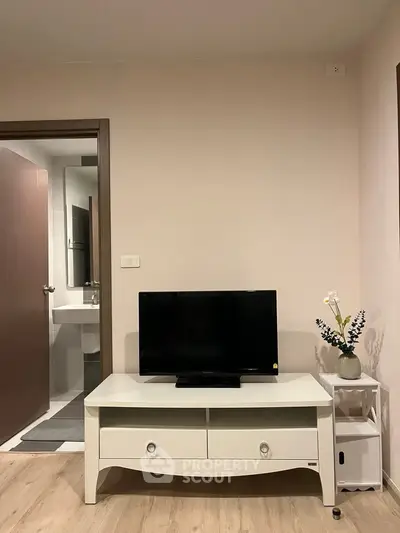 Cozy living room with TV and elegant decor, adjacent to a modern bathroom.