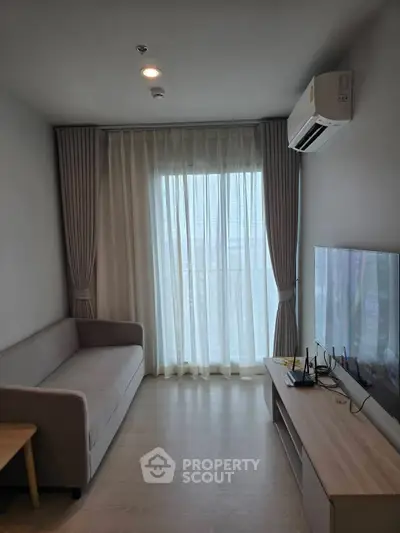 Modern living room with large window, sofa, and TV, featuring sleek design and natural light.