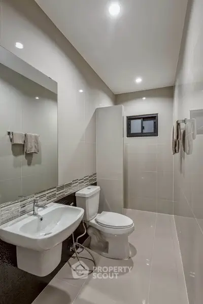 Modern bathroom with sleek fixtures and neutral tiles, featuring a spacious shower area.
