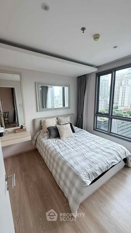 Modern bedroom with city view, large window, and stylish decor in a high-rise apartment.
