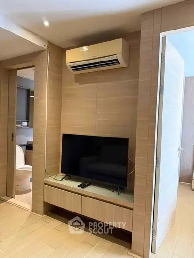 Modern living room with sleek TV setup and air conditioning, showcasing contemporary interior design.