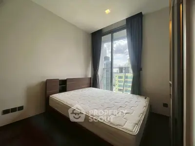 Modern bedroom with large window and city view, featuring a comfortable mattress and elegant curtains.