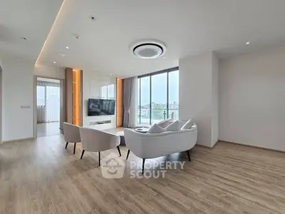 Spacious modern living room with elegant furniture and large windows offering a stunning city view.