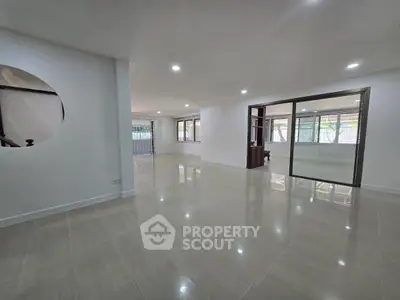 Spacious open-plan living area with glossy tiled floors and large windows.
