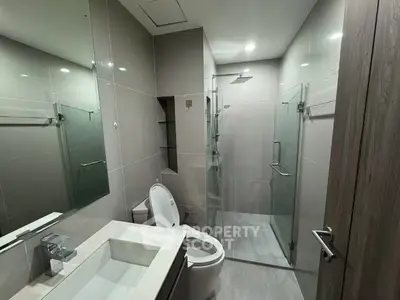 Modern bathroom with sleek fixtures and glass shower enclosure in a contemporary home.
