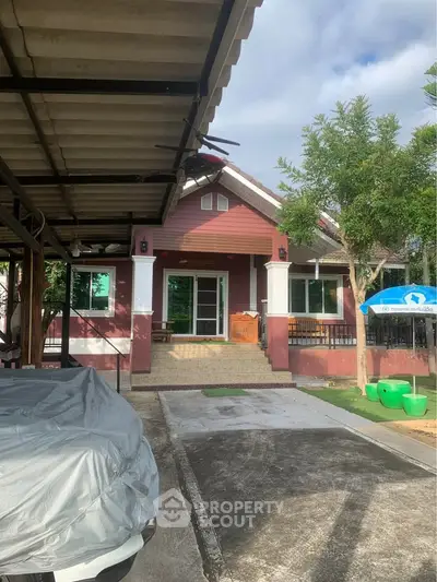 Charming single-story house with covered carport and lush greenery, perfect for serene living.