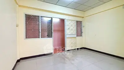 Spacious empty room with tiled floor and metal window grilles