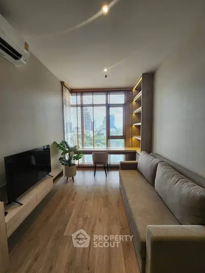 Modern living room with large window and city view, featuring cozy sofa and built-in shelves.
