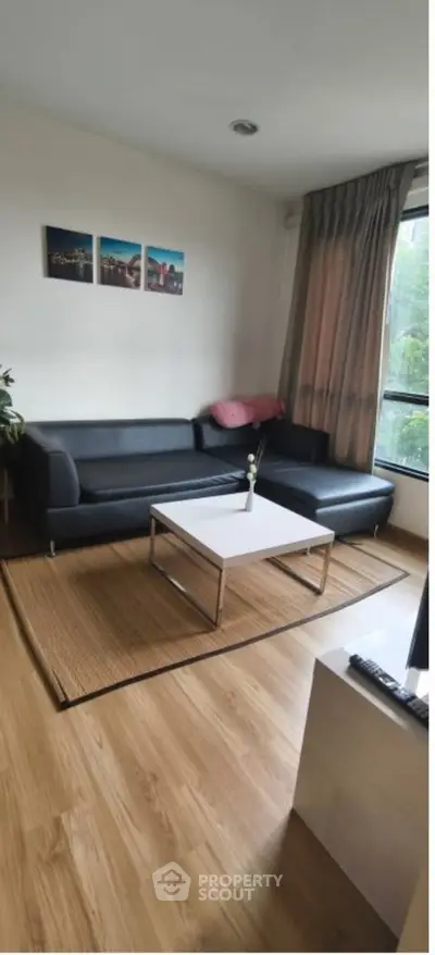 Modern living room with sleek black sofas and large window view