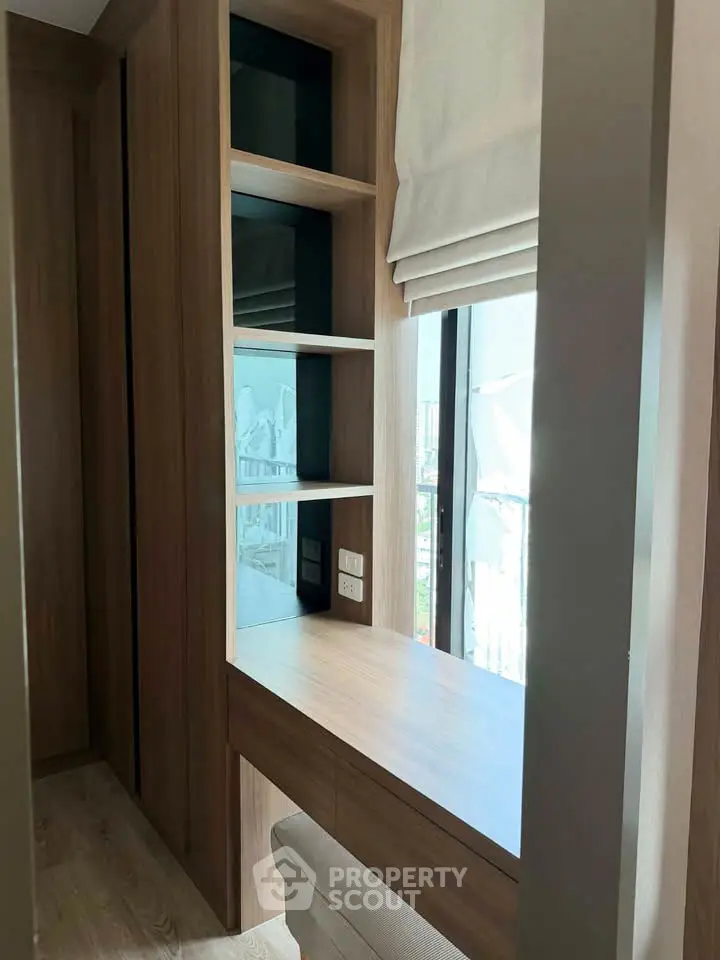 Modern study nook with built-in desk and shelves, featuring natural light from large window.