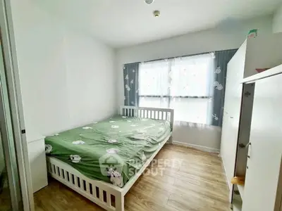 Cozy bedroom with wooden flooring and natural light, featuring a comfortable bed and ample storage space.