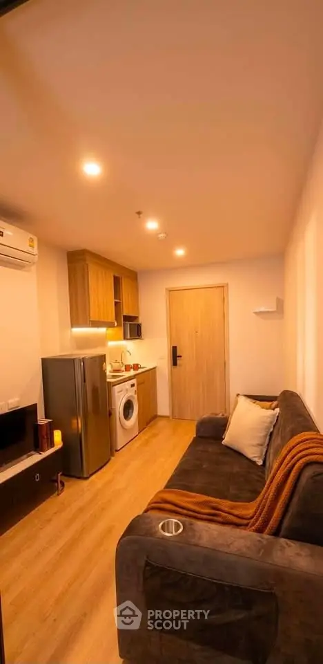 Cozy living room with integrated kitchen, featuring modern appliances and warm lighting.