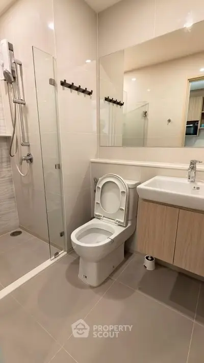 Modern bathroom with glass shower and sleek fixtures in contemporary apartment.