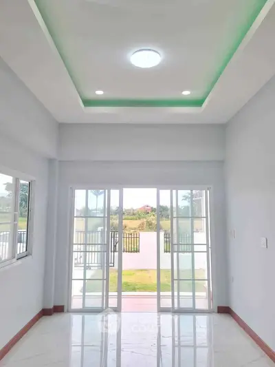 Bright and spacious room with large windows and modern ceiling lights, offering a serene garden view.
