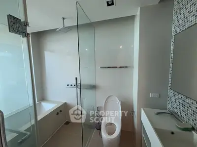 Modern bathroom with glass shower, bathtub, and sleek fixtures in a contemporary apartment.
