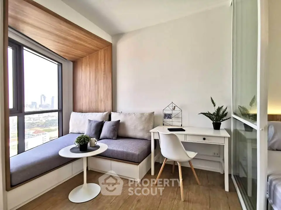 Modern study nook with city view, featuring cozy seating and sleek desk in a bright apartment.