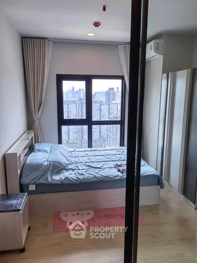 Modern bedroom with city view, featuring large window and stylish decor.