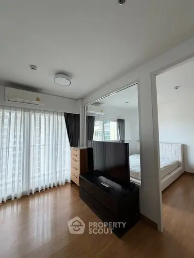 Modern bedroom with wooden flooring, large windows, and sleek furniture in a bright apartment.