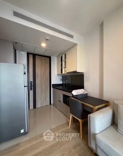 Modern compact kitchen with sleek appliances and cozy dining area in a stylish apartment.
