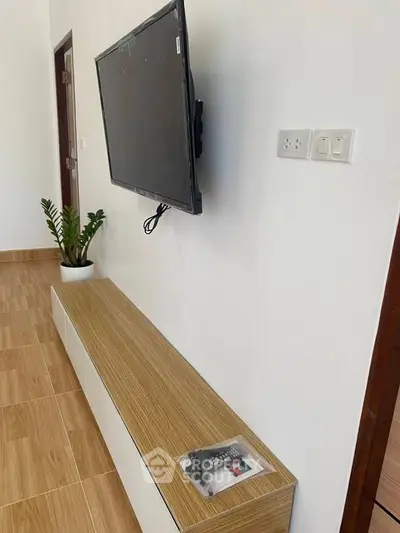 Modern living room with mounted TV and sleek wooden flooring.