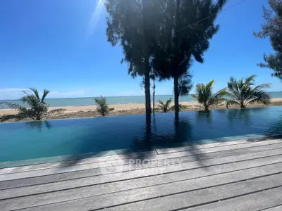 Stunning beachfront infinity pool with ocean view and palm trees under clear blue sky.