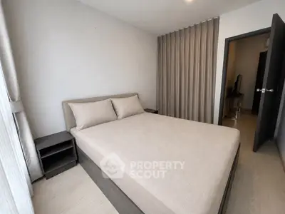 Modern bedroom with neutral tones and minimalist design, featuring a comfortable bed and sleek furnishings.