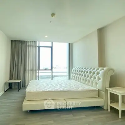Spacious bedroom with elegant bed and large window offering natural light.