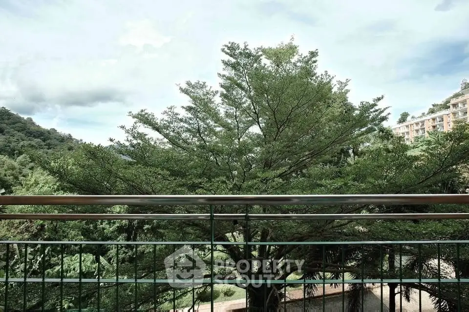 Scenic balcony view with lush greenery and distant building, perfect for nature lovers.