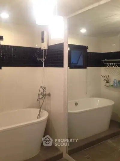 Modern bathroom with sleek bathtub and stylish black tile accents.