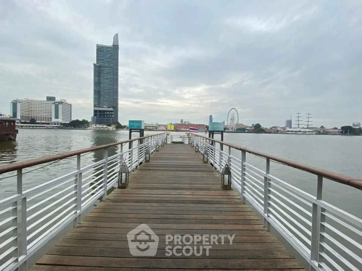 Scenic waterfront view with modern buildings and a wooden pier extending into the water.
