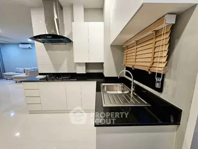 Modern kitchen with sleek black countertops and gas stove in open layout.