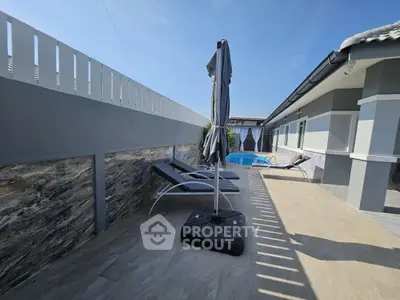 Modern villa with pool and sun loungers in sunny outdoor space