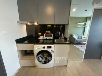 Modern compact kitchen with washing machine and cozy living room view