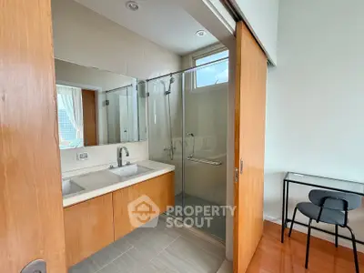 Modern bathroom with wooden accents and glass shower enclosure
