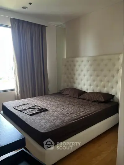 Luxurious bedroom with plush headboard and natural light, perfect for relaxation and comfort.